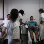 Una persona che dona il sangue circondata da personale sanitario