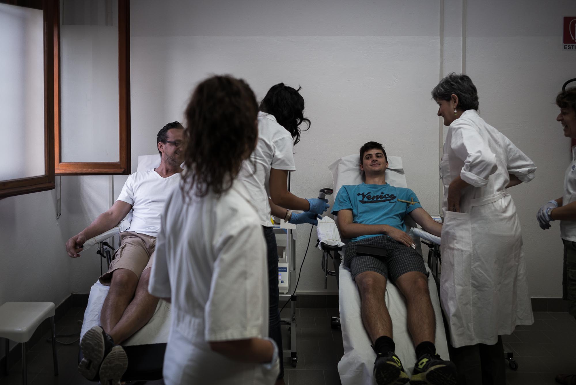 Una persona che dona il sangue circondata da personale sanitario