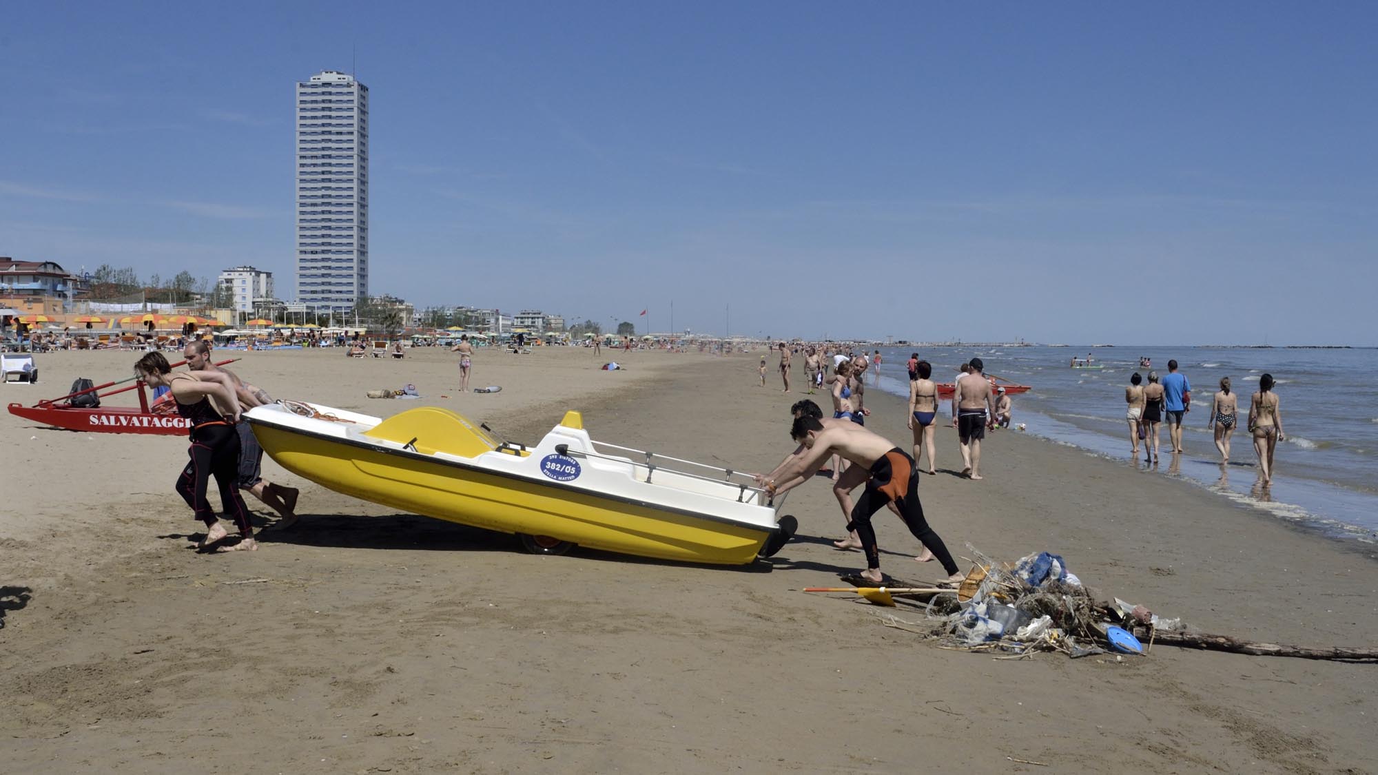 Una persona spinge un pedalò fuori dal mare sulla spiaggia
