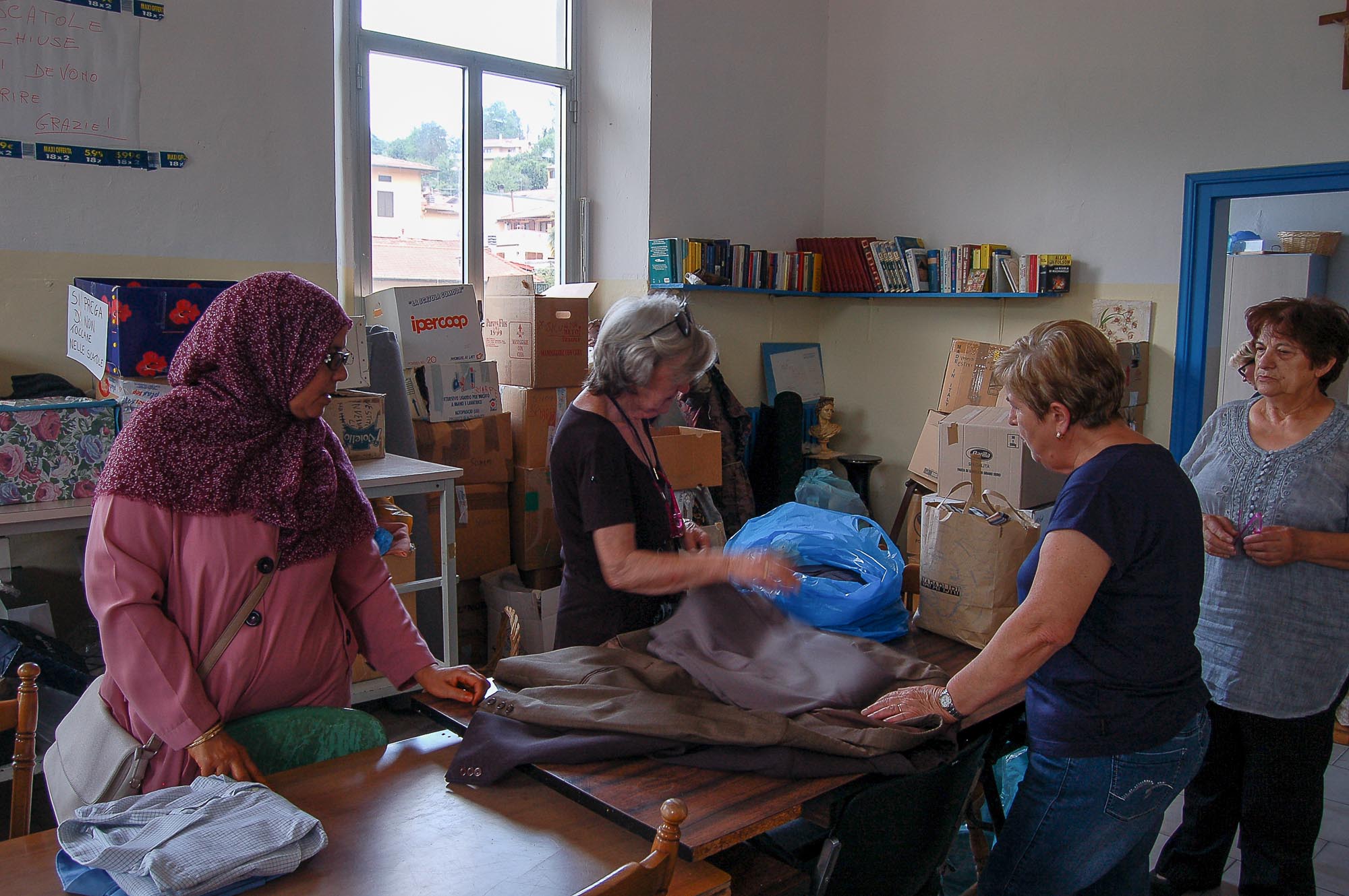 Persone che piegano dei vestiti attorno a un tavolo.