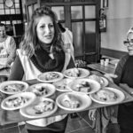 volontaria di una mensa sociale mentre porta vassoio carico di piatti pronti