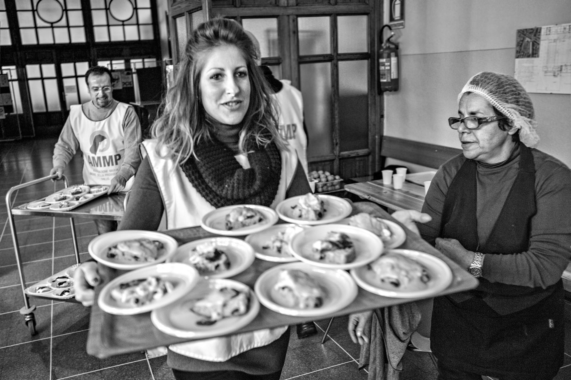 volontaria di una mensa sociale mentre porta vassoio carico di piatti pronti