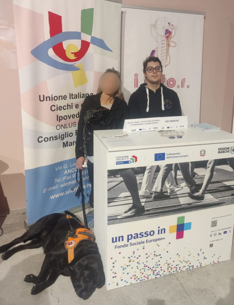 Foto di Luca Manganelli insieme a una utente di Uici Marche e a un cane guida durante un'iniziativa dell'associazione