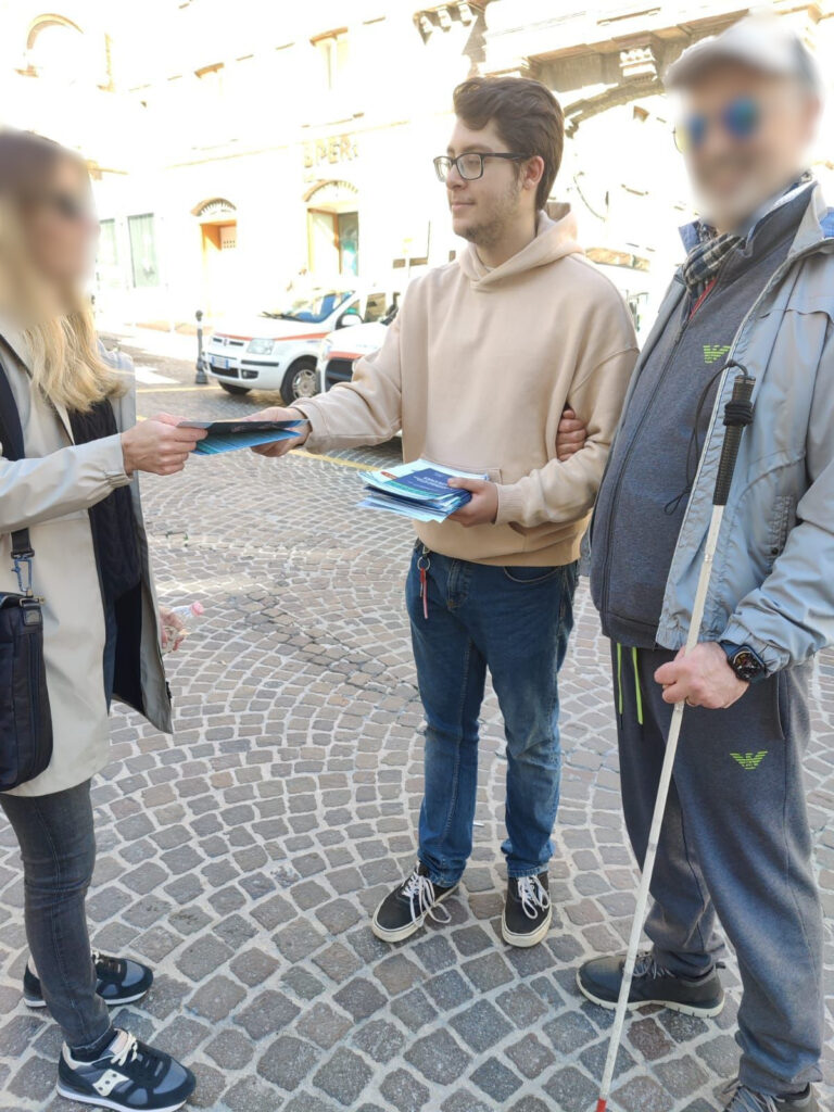 Foto di Luca Manganelli insieme a un utente di Uici Marche, mentre distribuisce volantini informativi