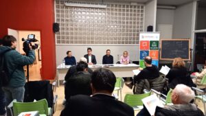 la sala della conf. stampa con platea di giornalisti e volontari di fronte al tavolo dei relatori