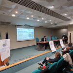 l'interno dell'auditorium con una relatrice al leggìo