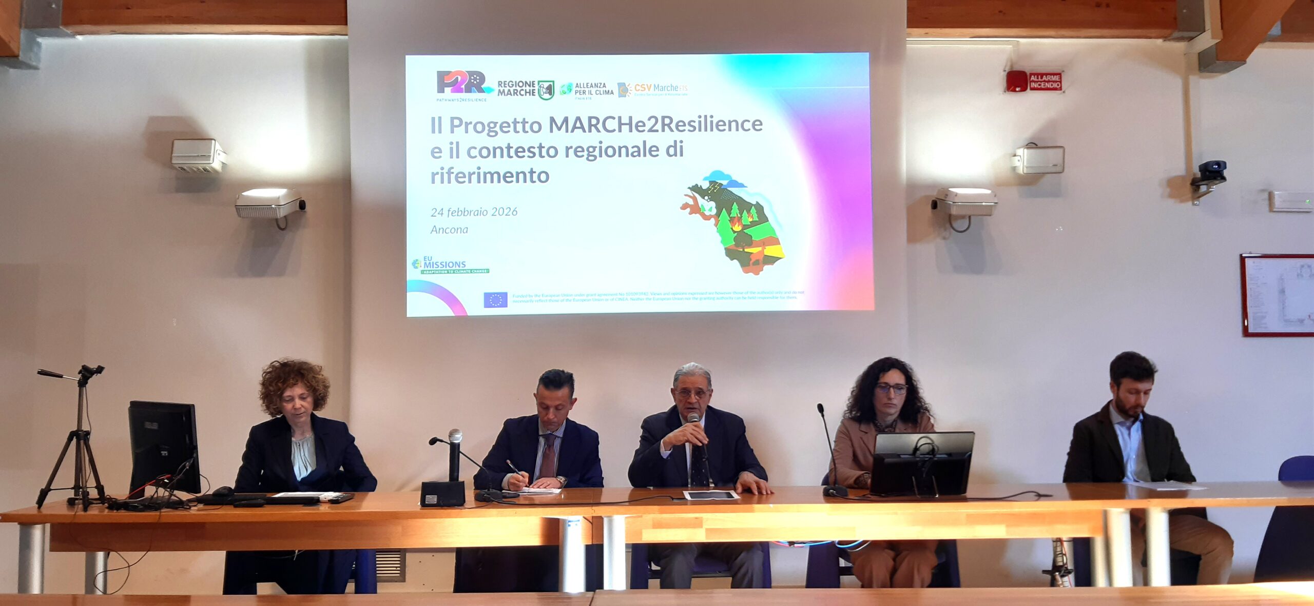 tavolo con 5 relatori durante l'intervento di uno