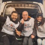 Tre persone sedute sul retro di un furgone aperto
