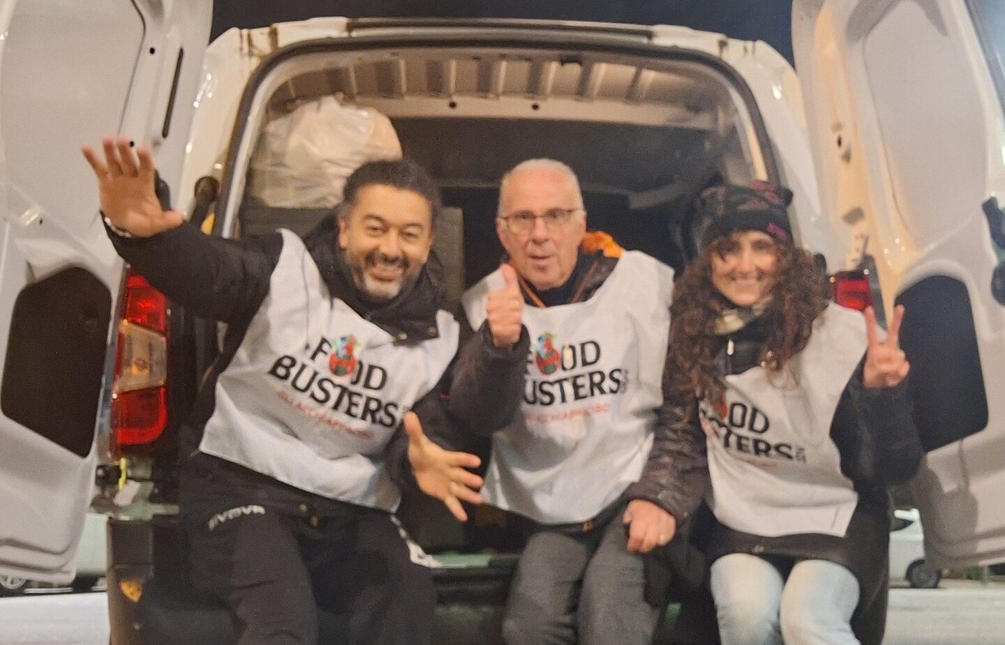 Tre persone sedute sul retro di un furgone aperto