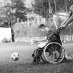 una persona in sedia a rotelle che insegue un pallone