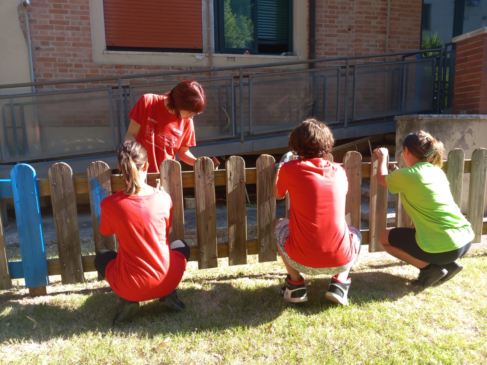 una squadra di giovani partecipanti al progetto mentre dipingono una staccionata