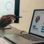 una mano indica un grafico sullo schermo di un pc