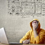 un ragazzo dubbioso davanti a un pc immagina il lavoro da fare per un sito web