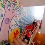una squadra di giovani partecipanti al progetto vicino a una parete dipintacon murales