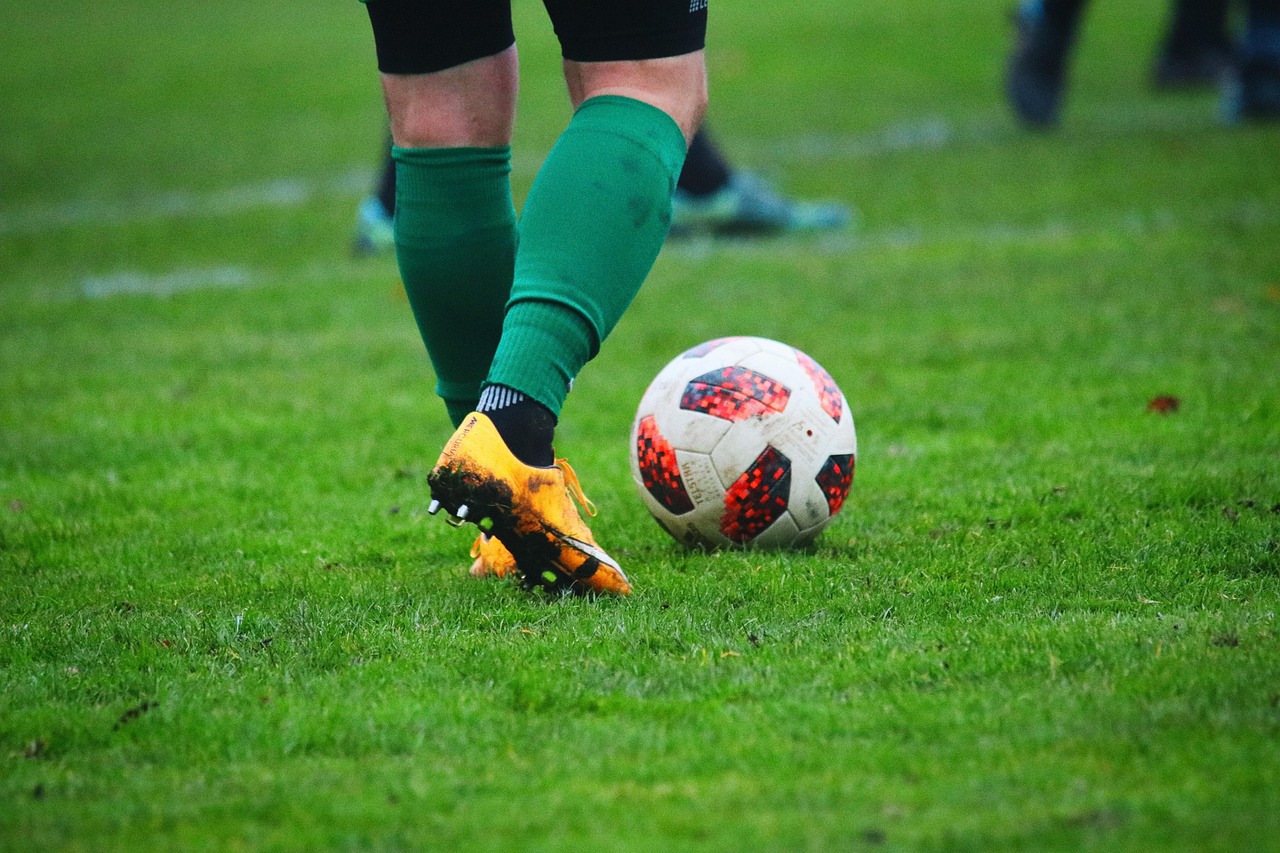 le gambe di un calciatore davanti a un pallone sul campo da gioco