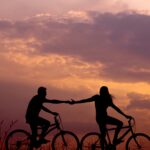Due persone in bicicletta al tramonto
