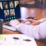 una persona di spalle davanti al pc durante una videocall