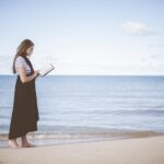 una ragazza legge un libro in riva al mare