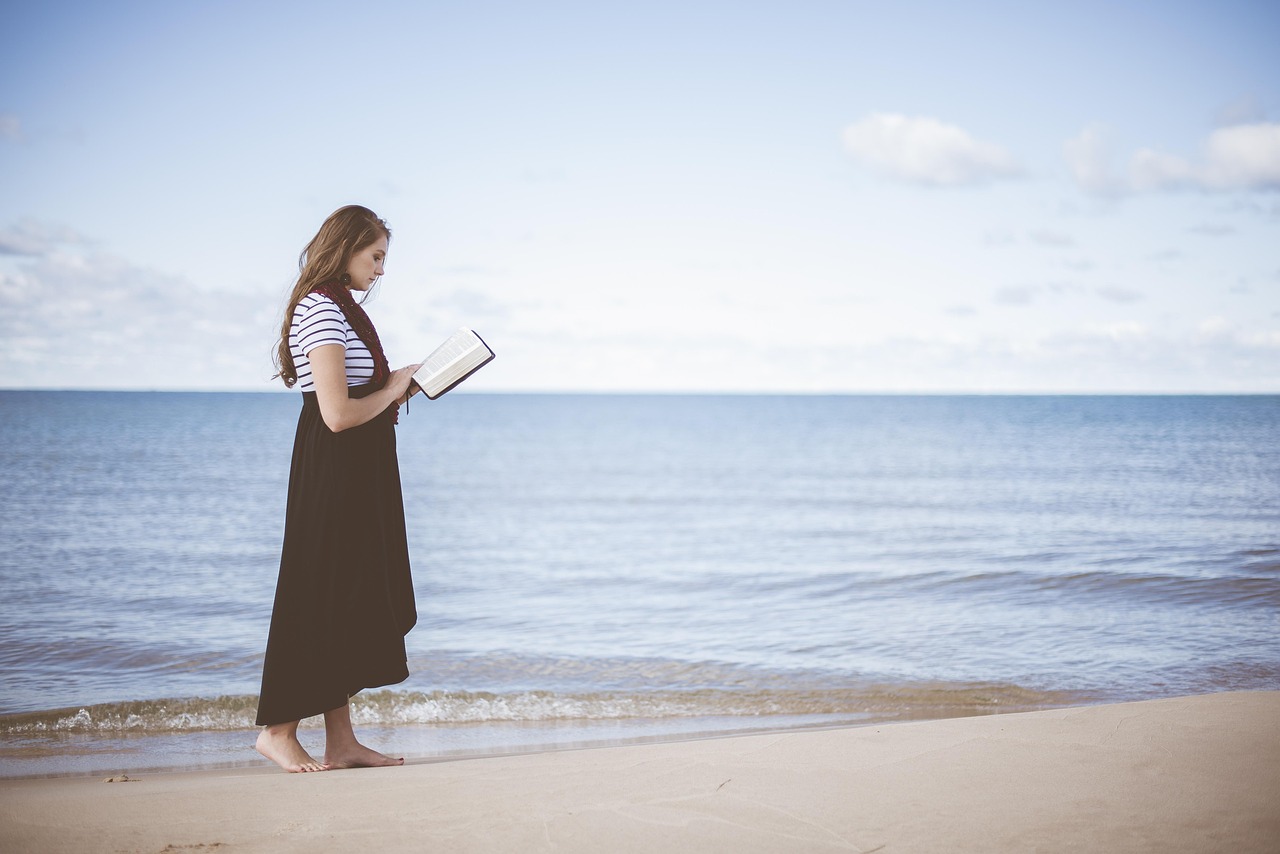 una ragazza legge un libro in riva al mare