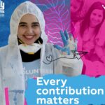 una volontaria con la tuta bianca e la mascherina fa il cinque con la mano