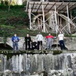 Quattro persone al lavoro davanti a una struttura in restauro