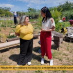 la presidente dell'associazione e la giornalista in piedi nell'orto sociale durante l'intervista