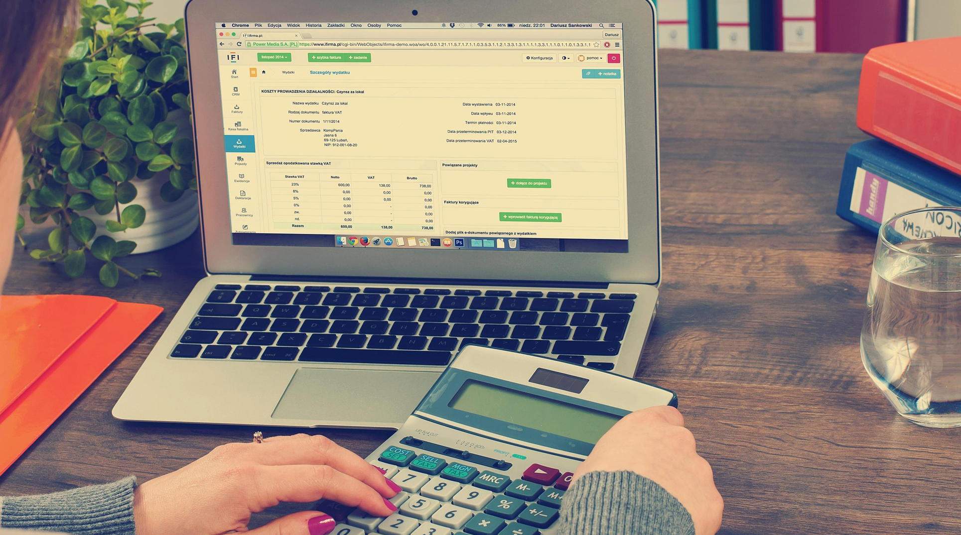 due mani stanno usando una calcolatrice di fronte ad un pc aperto