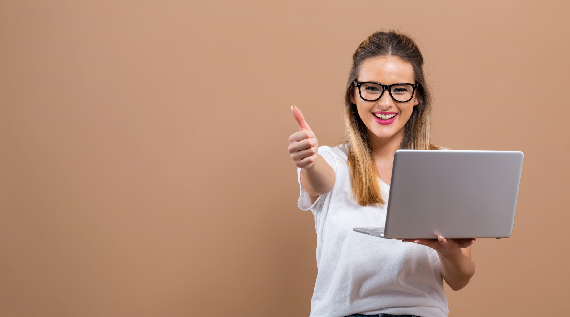 una giovane ragazza sorridente con un pc in mano e nell'altra mano il pollice alto in segno cincente