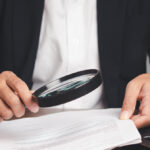 una persona legge un documento con una lente d'ingrandimento