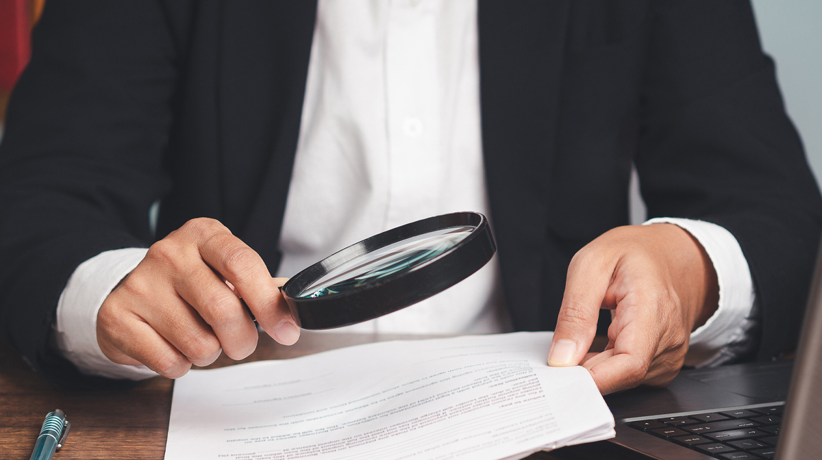 una persona legge un documento con una lente d'ingrandimento