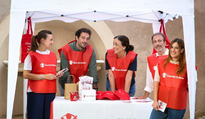 Un gruppo di persone ad un banchetto di Save the Children