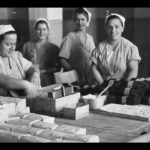 Una foto in bianco e nero di donne al lavoro attorno a un tavolo.