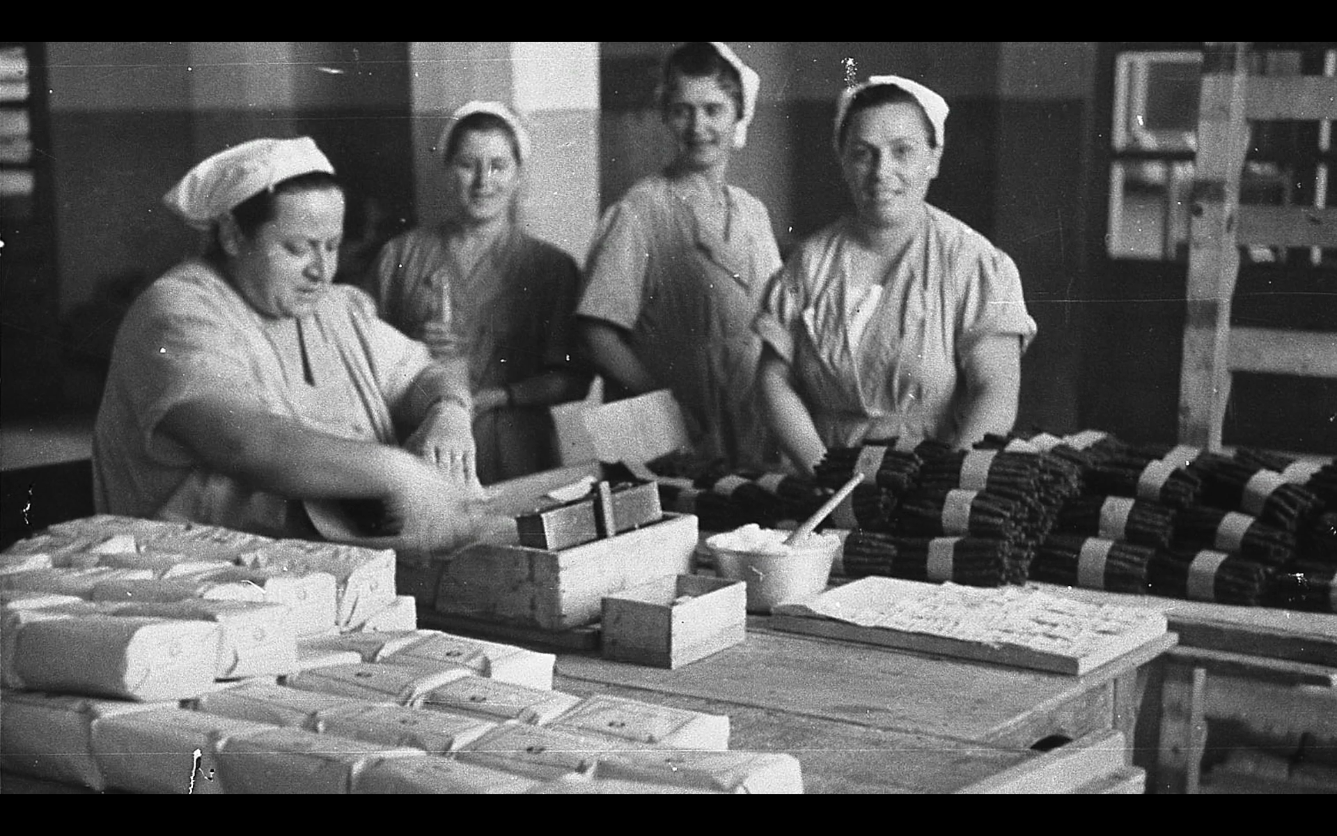 Una foto in bianco e nero di donne al lavoro attorno a un tavolo.