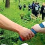 due mani si passano un testimone in un bosco