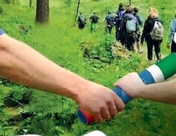 due mani si passano un testimone in un bosco