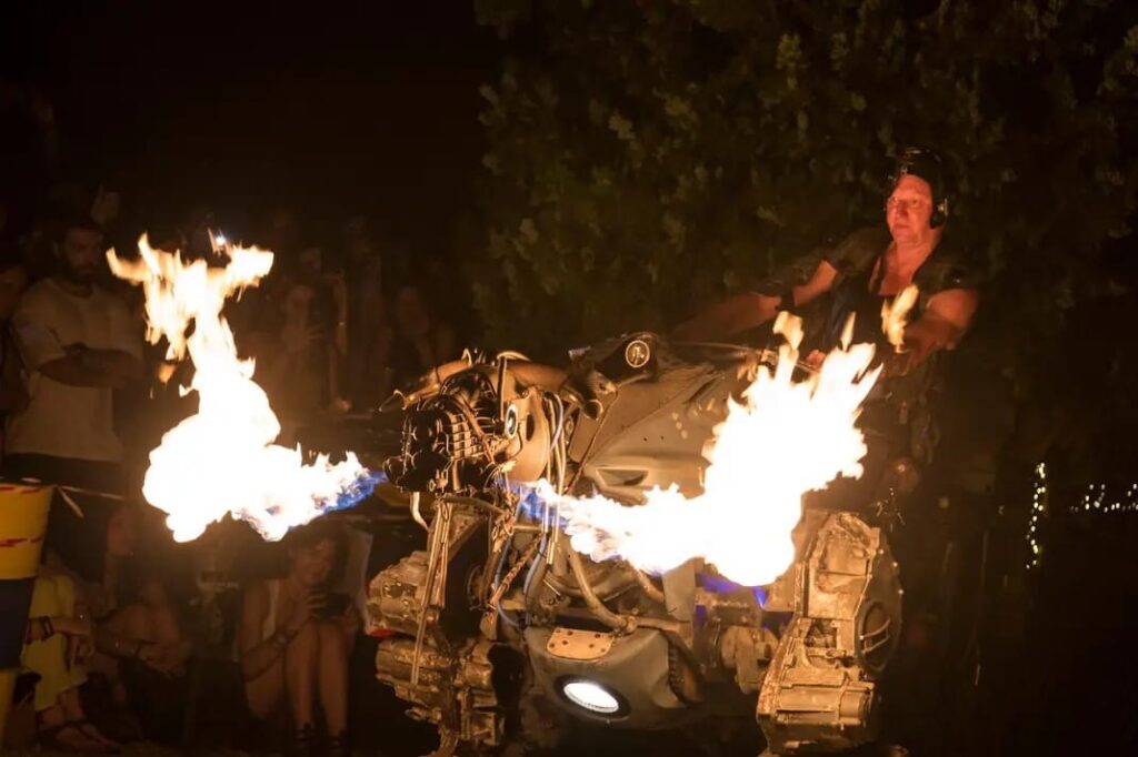 Foto di un artista di strada con un toro meccanico e delle fiamme