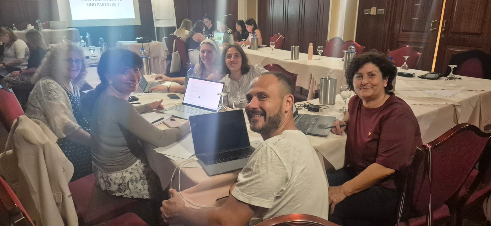 PErsone al lavoro attorno a un tavolo, con dei computer