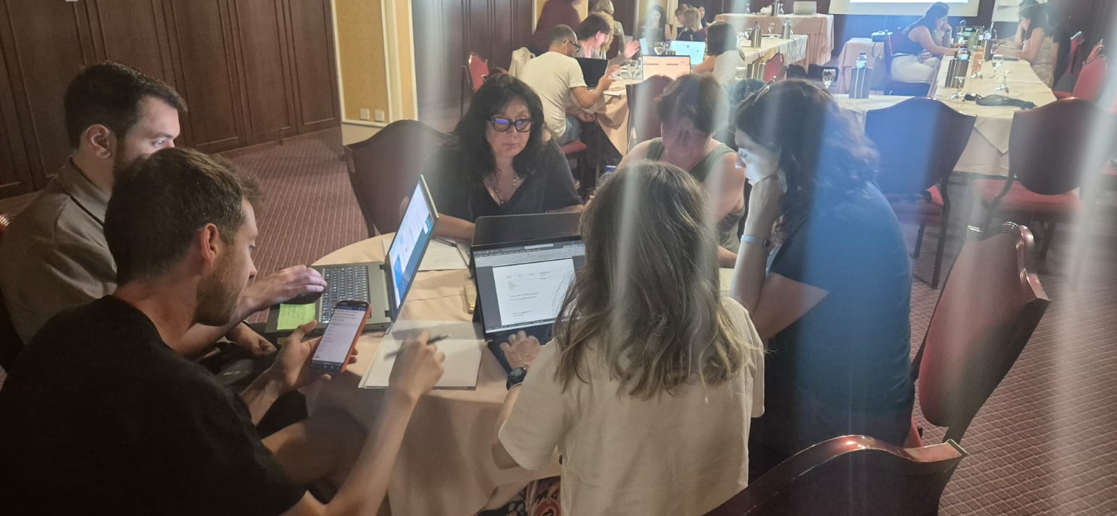 Persone al lavoro attorno a un tavolo con dei computer