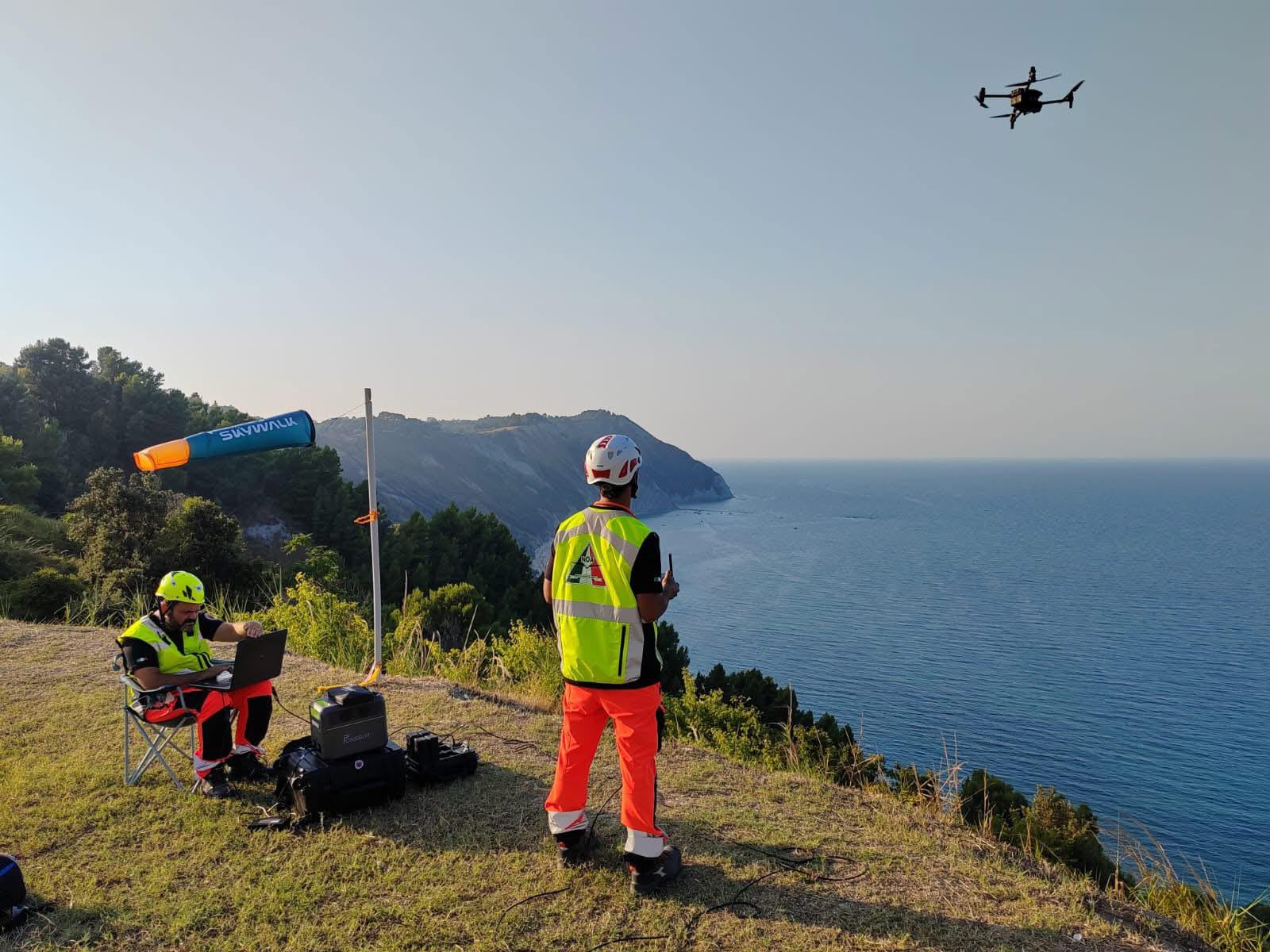 Una persona telecomanda un drone su una collona sopra il mare