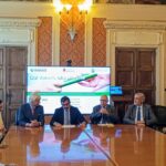 un lungo tavolo rettangolo attorno cui sono seduti relatori e partecipanti