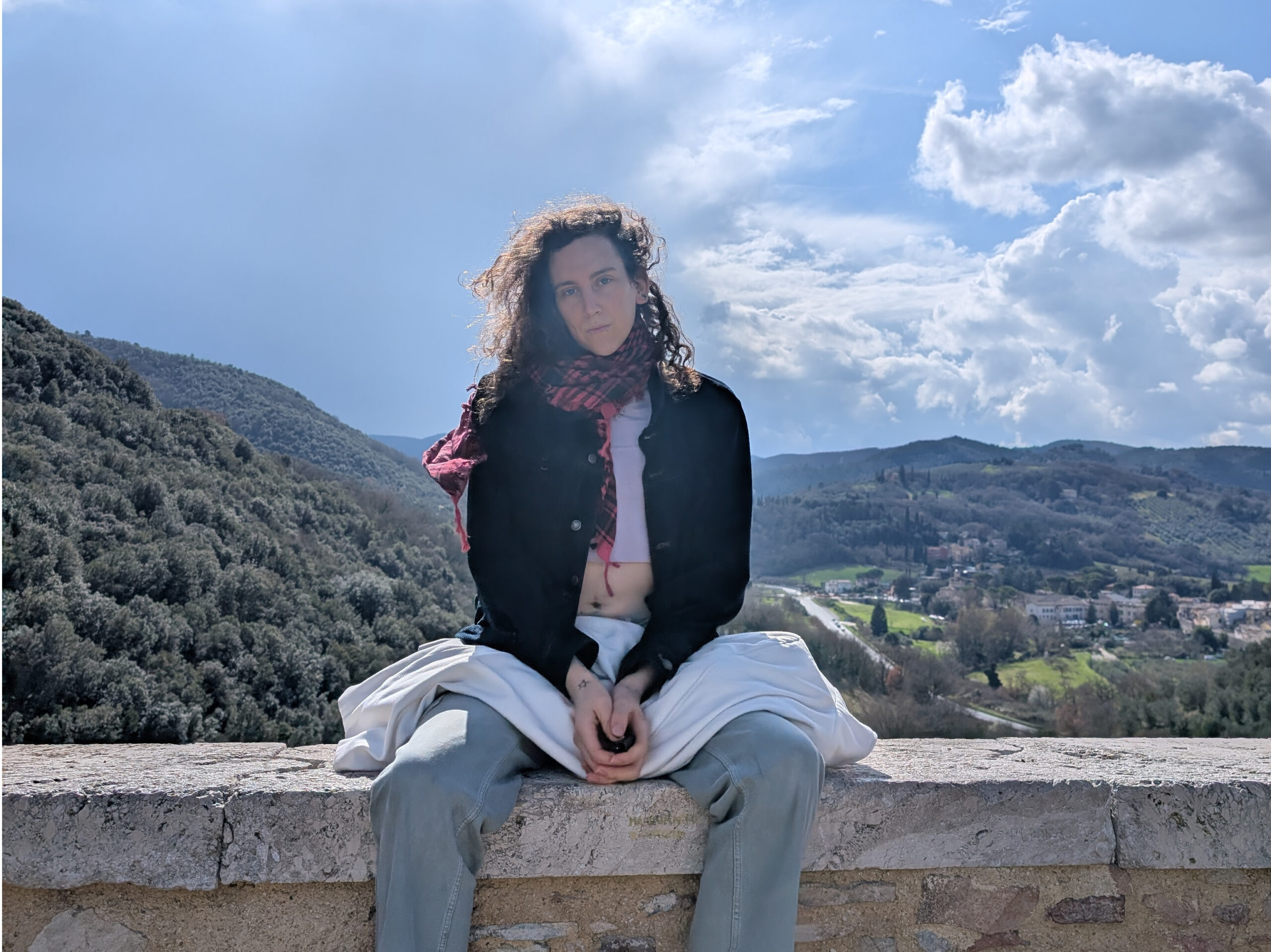Foto di Lara Bouchière-Ben Méziane seduta sopra un muretto con sullo sfondo delle colline
