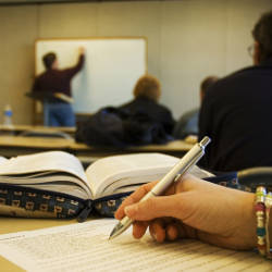 un'aula scolastica con un prof che scrive alla lavagna