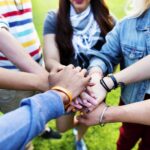 gruppo di giovani disposti a cerchio con le mani unite al centro