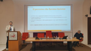 Giacomo Ricciutelli al leggio a sinistra del tavolo dei relatori