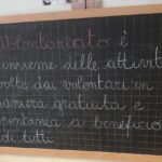 una lavagna nera con una scritta di gesso bianco sul tema volontariato