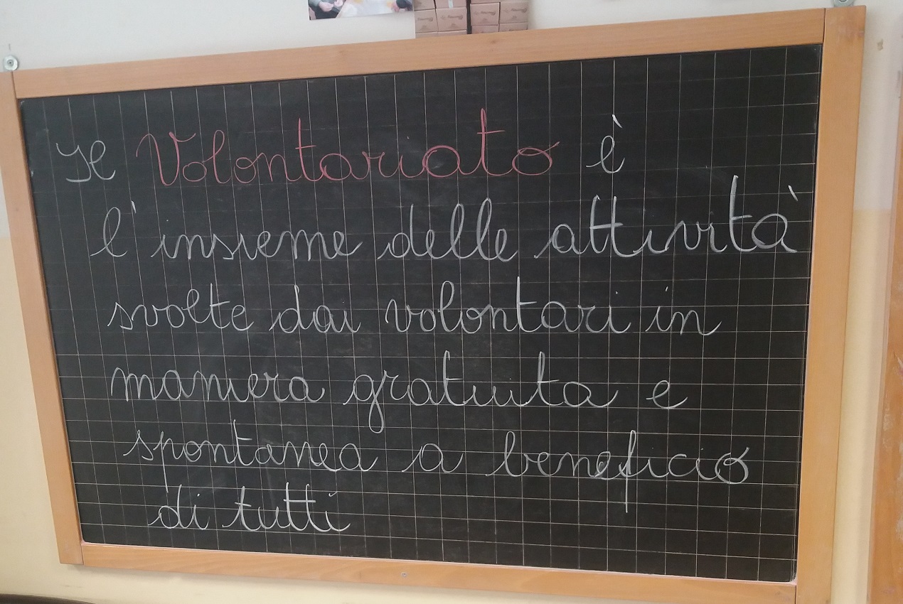 una lavagna nera con una scritta di gesso bianco sul tema volontariato