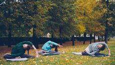 Tre persone praticano yoga in un prato.