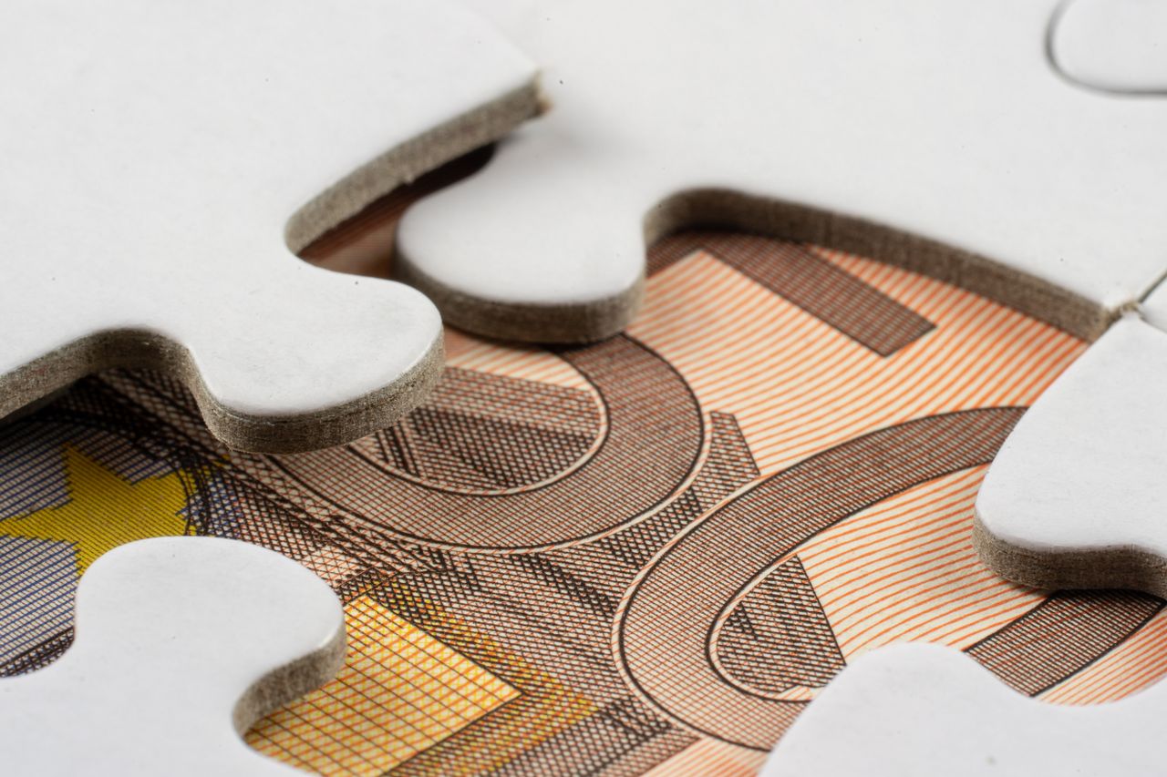 Una banconota incastrata sotto allo spazio vuoto di un puzzle