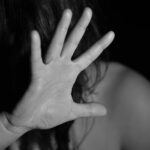 Una donna si protegge il volto alzando la mano.