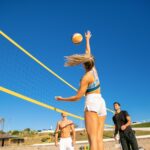 Un gruppo di adulti giocano a beach volley, con una schiacciata sotto rete